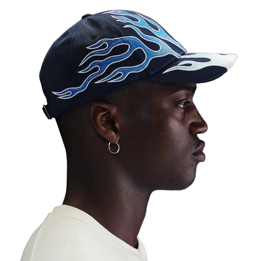 Nike Flame Cap in Navyblau mit hellblauen Flammenstickereien – seitliche Ansicht auf einem Model getragen, stylische Streetwear-Kappe mit verstellbarem Verschluss.