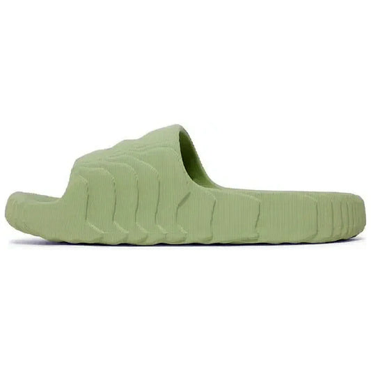 Adidas Adilette 22 Slides in Magic Lime, Seitenansicht der hellgrünen Sandale mit markantem, wellenförmigem Design und strukturierter Oberfläche, auf weißem Hintergrund fotografiert.