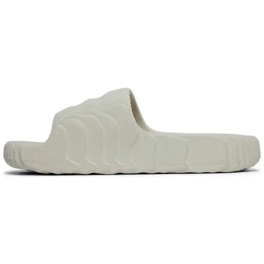 Adidas Adilette 22 Slides in Aluminium-Grau, seitliche Rückansicht der Sandale auf weißem Hintergrund, modernes Design mit 3D-Struktur und wellenförmigen Linien.