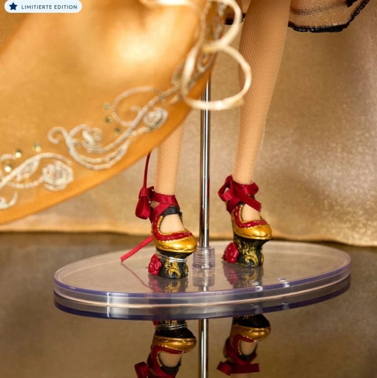Disney Designer Collection Belle Puppe – Detailaufnahme der limitierten Edition aus Die Schöne und das Biest mit gold-roten High Heels und Stickereien des Kleids, Nahaufnahme auf Sammlerständer