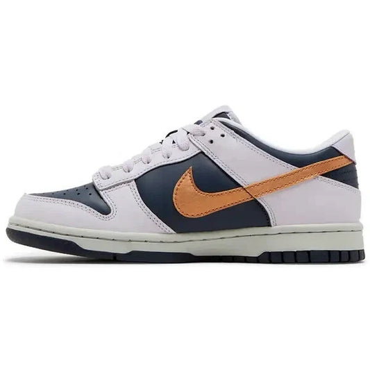 Nike Dunk Low SE GS Copper Swoosh – Seitenansicht des Jugend-Sneakers in Grau und Dunkelblau mit glänzend kupferfarbenem Nike-Swoosh, dargestellt auf weißem Hintergrund.