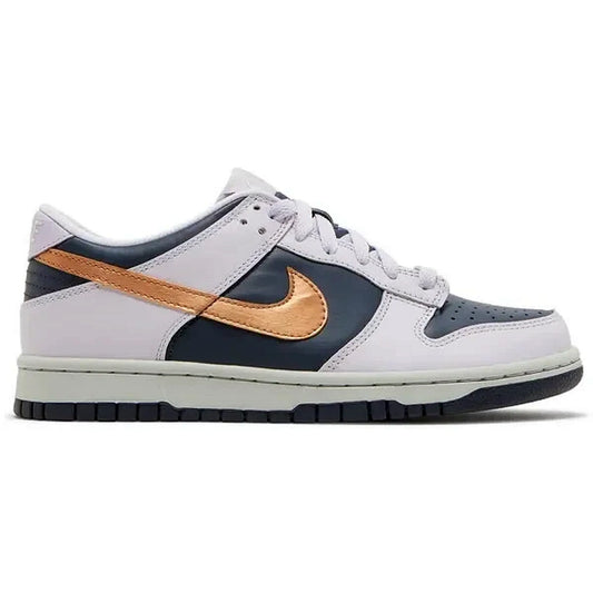 Nike Dunk Low SE GS Copper Swoosh – seitliche Produktaufnahme des grauen und dunkelblauen Sneakers mit metallisch kupferfarbenem Swoosh, flach fotografiert auf weißem Hintergrund.