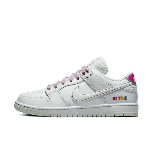 Nike SB Dunk Low Pro Be True – seitliche Nahaufnahme des weißen Sneakers mit Regenbogen-Schriftzug „Be True“, pastellfarbenem Swoosh und rosa Schnürsenkeln auf weißem Hintergrund.