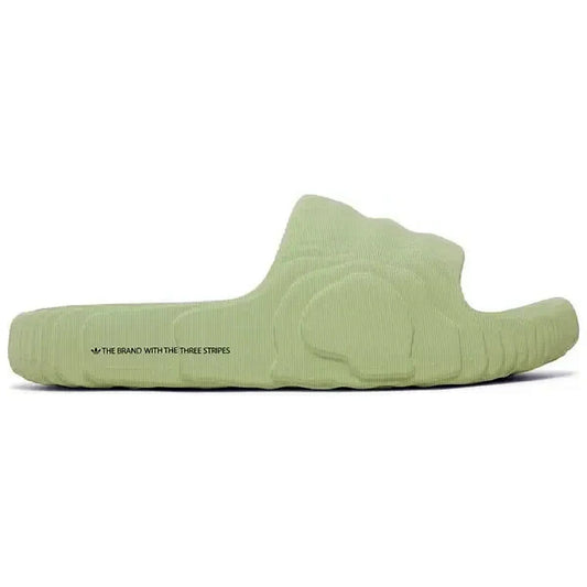Adidas Adilette 22 Slides in Magic Lime, Seitenansicht der hellgrünen Sandale mit strukturiertem, futuristischem Design und dem Schriftzug „The Brand with the Three Stripes“, auf weißem Hintergrund.