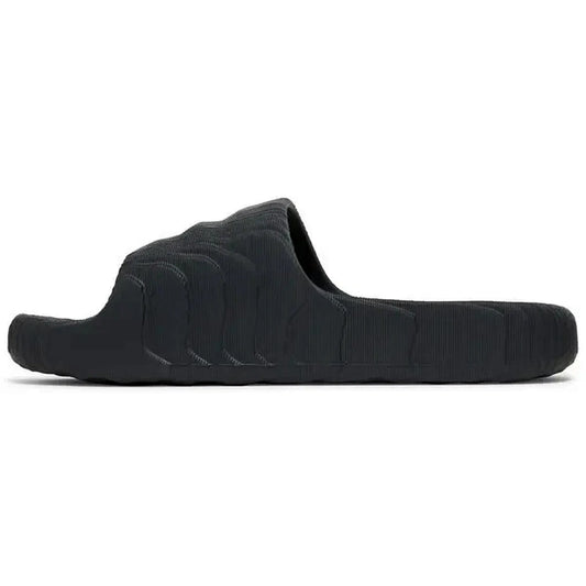 Adidas Adilette 22 Slides in Carbon-Schwarz, Seitenansicht der Sandale mit futuristischer, wellenförmiger Struktur und minimalistischem Design, auf weißem Hintergrund fotografiert.