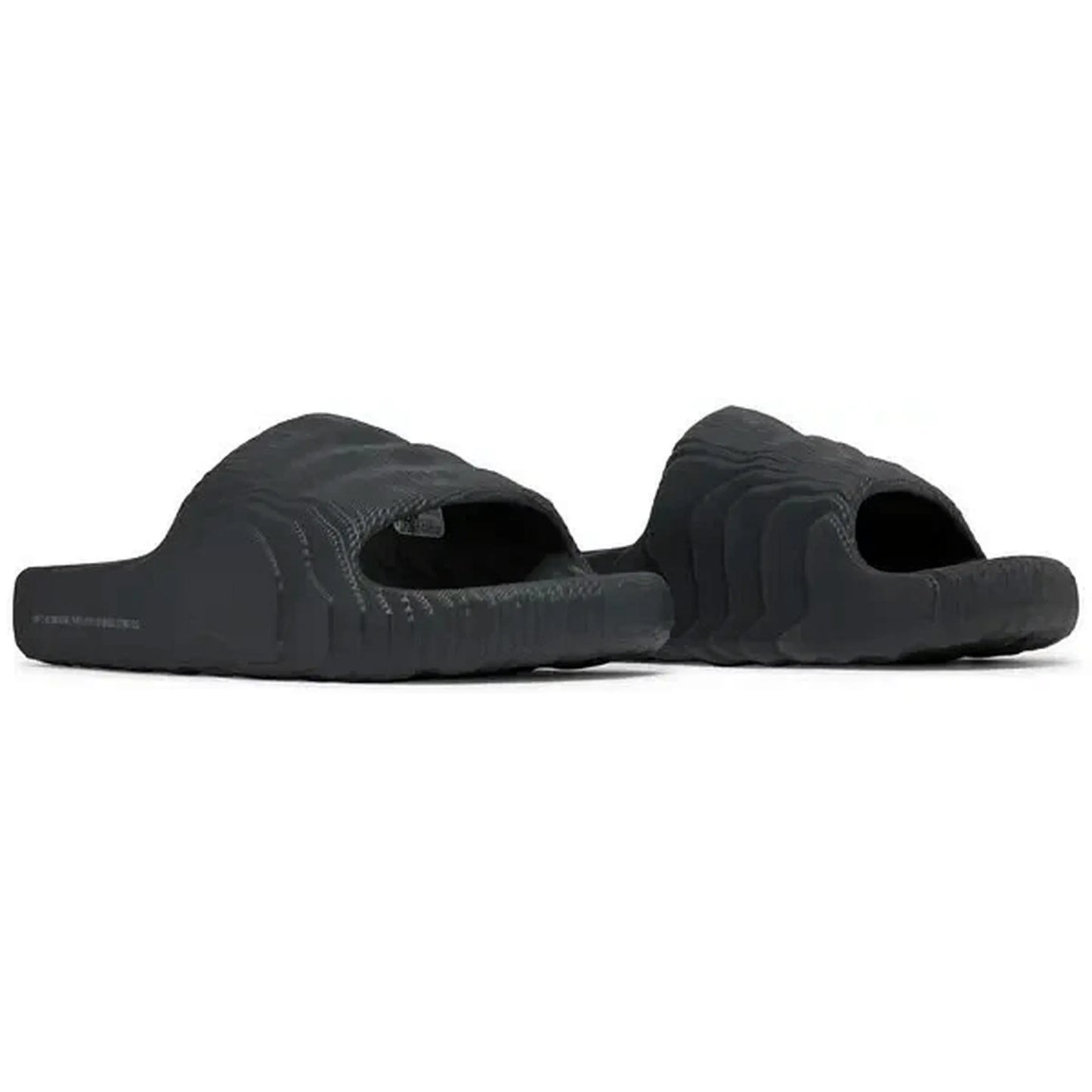 Adidas Adilette 22 Slides in Carbon-Schwarz, Paaransicht der Sandalen in schräger Perspektive mit strukturiertem, futuristischem Design, präsentiert auf weißem Hintergrund.