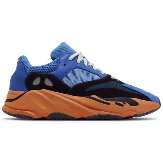 Adidas Yeezy Boost 700 Bright Blue, Seitenansicht des Sneakers mit leuchtend blauer Mesh-Oberfläche, schwarzen Overlays und orangefarbener Boost-Zwischensohle auf weißem Hintergrund.