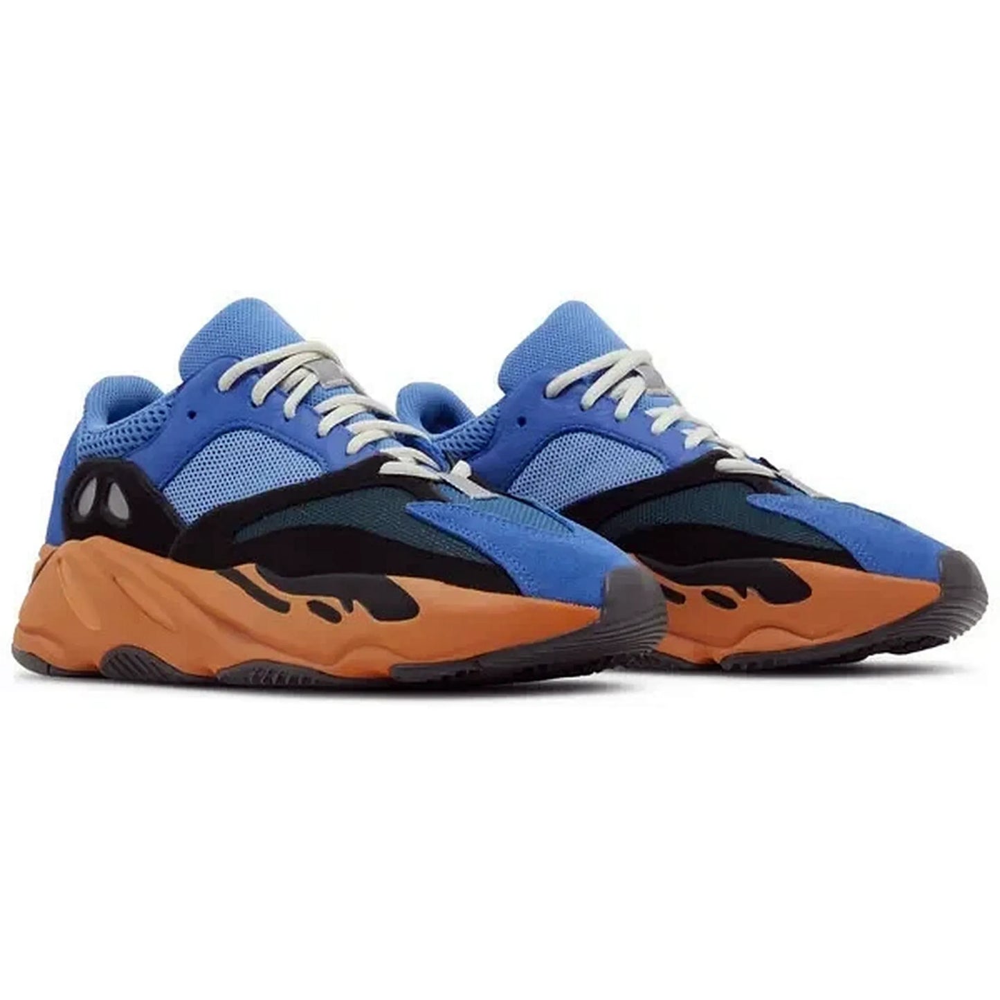 Adidas Yeezy Boost 700 Bright Blue, Paar Sneakers in schräger Vorderansicht mit blauer Mesh-Oberfläche, schwarzen Overlays, weißen Schnürsenkeln und orangefarbener Zwischensohle auf weißem Hintergrund.
